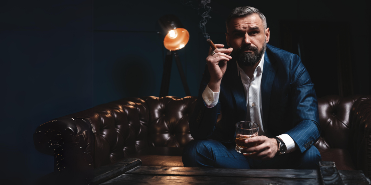 Man drinking whiskey in a whiskey bar smoking a cigar